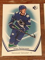 Close-up of an Elias Pettersson hockey card with SP branding, showing player in Vancouver Canucks uniform in action pose.