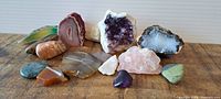 Front and top view of various polished and raw rocks and crystals arranged on a wooden surface, showing color and texture variety