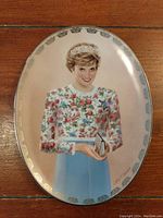 Front view of the oval porcelain plate showing Princess Diana in a floral dress and tiara against a cream background with gold border.