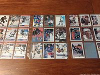 Full view of all 27 Wayne Gretzky hockey cards laid out on a table, showing a wide variety of cards in protective sleeves.