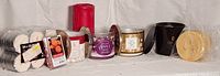 Photo of assorted candles and wax melts including Bath & Body Works jar candles and Ikea tealights arranged in a row against a white background.