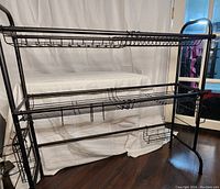 Full view of the adjustable over sink draining rack showing two wire mesh shelves, hanging hooks, and multiple holders including a basket for cutting board or utensils.