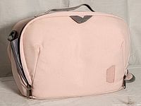 Front side view of the small pink camera bag highlighting the fabric, shape, and zipper details