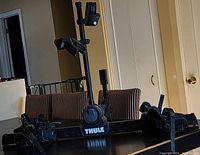 Side view of the Thule two-bike roof rack carrier showing wheel trays and vertical mast with frame clamps