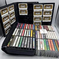 Photo showing a folding case with 15 'Rock N' Roll' cassette tapes and two rows of various cassette tapes in plastic cases.