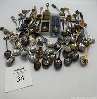 Overview image of the lot showing approximately 40+ small collector spoons with a variety of decorations including landmarks, crests, and enamel details.