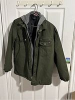 Front view of the Dickies jacket hanging on a hanger showing olive green jacket with grey hoodie liner.