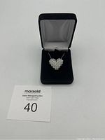 Heart-shaped silver necklace displayed in an open black velvet jewelry box with white satin interior and auction card number.