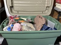 Large plastic tote filled with yarn, fabric pieces, and sewing supplies from above view