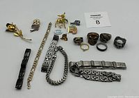 Full view of assorted rings, bracelets, and pins laid out on white background.