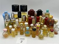 The full lot of vintage perfume bottles arranged in rows, showing a variety of colors, shapes, and sizes including clear glass, amber tones, and decorative tops.