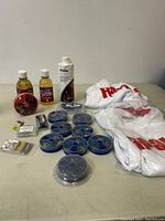 Full view of the lot with fishing tackle containers, bottles, hooks, and two white Rapala XL t-shirts.