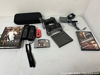 Lot contents arranged showing all controllers, game cartridges, game case, movie DVDs, zippered case and power adapter