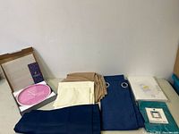 Wide view showing boxed pink wall clock and various curtain panels and pillowcases