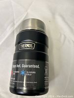 Front view of black Thermos food jar showing brand logo and temperature retention details.