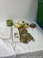 Overview of lot showing multiple rolls of tape and a box containing adhesive tile samples.