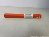 Full view of the orange rectangular protective case for the drill bit on a light surface.
