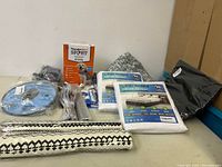 Photo showing assorted pet and home items including Ergo Bedding mattress protector packages, pet anxiety collar package, pet feeding dish, and folded textiles.