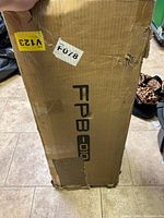 Box containing parts of the S-shaped storage rack, showing some wear and damage to cardboard packaging.