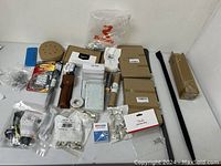Overview of the lot showing several boxed items, a bag of metal screws, sanding pads, and an assortment of metal and plastic tool accessories