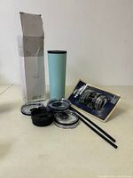 The light blue 28oz slim Classic Tumbler with multiple interchangeable lids, straws, and Yeti Rambler cap shown with original packaging box.