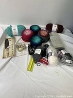 Full lot overview showing all yarn skeins and bundled craft supplies on white cloth