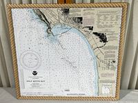 Framed nautical chart map of Half Moon Bay, California with rope-style wood frame and plexiglass cover, showing coastal and bathymetric details.