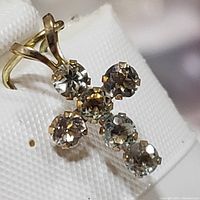 Close-up image of a yellow gold cross pendant set with round aquamarine stones seen at an angle.