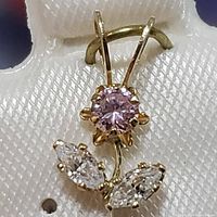Close-up image of the 10K yellow gold flower pendant showing the pink round center cubic zirconia stone and two clear marquise-shaped cubic zirconia stones.