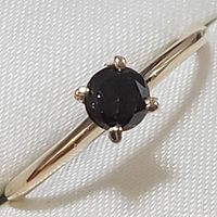 Close-up image of the 10K yellow gold ring showcasing the black round diamond in a four-prong setting on a smooth band.