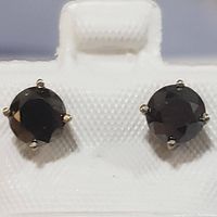 Pair of round-cut black diamond stud earrings set in 14K white gold shown on a white textured holder.