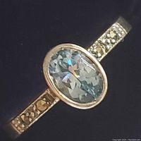 Close-up photo of the sterling silver ring showing oval blue topaz gemstone and marcasite accents on the band from front angle.