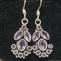 Pair of sterling silver earrings with multiple amethyst stones displayed on black background, demonstrating the front view and detail of the stones and setting.