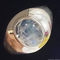 Front view of sterling silver ring with oval moonstone showing the stone's translucent qualities and silver band curvature.