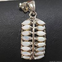 Close-up front view of the rectangular sterling silver pendant with white opal stones arranged along a central silver bar