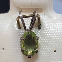 Front view of the sterling silver peridot pendant showing the oval green peridot held by six prongs and the silver bail.