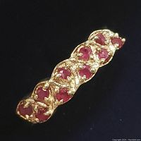 Close-up photo of sterling silver ruby ring showing heart-shaped red ruby stones set in lattice pattern.
