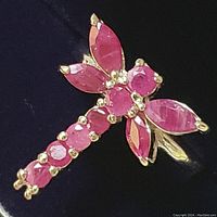 Close-up of the ruby dragonfly ring showing ruby stones and sterling silver prong settings.
