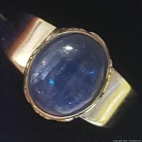 Close-up image of sterling silver ring with blue oval tanzanite cabochon gemstone on a polished band.