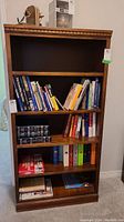 Full view of the vintage wood bookcase filled with books showing its overall size and condition.