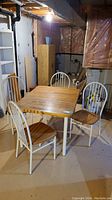Full set showing table with wood top and white metal legs, four chairs around the table; basement setting