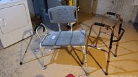 Photo showing folding walker, shower seat, and walking cane on a concrete floor near laundry appliances.