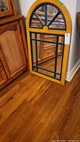 Full view of the wood framed mirror leaning against furniture on hardwood floor.