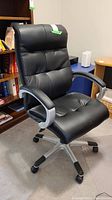 Front view of black padded office chair with cushioned seat and back, armrests, and caster wheels.