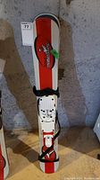 Full view of one of the skis showing the red and white design with Alphabet of TwinBoard logo, bindings, and carry strap