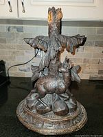 Overall view of the hand carved wooden sculpture showing mythical animal, tree, and base