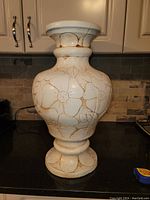 Full frontal view of large ceramic vase showing bulbous shape, wide base, and floral relief decoration.