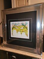 Image showing the full framed print from a slight angle with visible metallic frame and black and white matting.