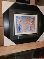 Photo of the framed fine art print leaning against a wall, showing full frame with packaging corners still attached.