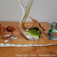 Front and size view of three glass figurines: one large green Murano style fish in the middle and one amber glass bird to left and one blue glass bird to right